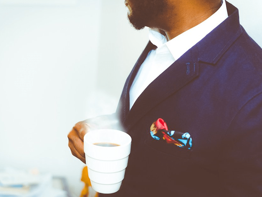 an image of a man in a business suit drinking coffee