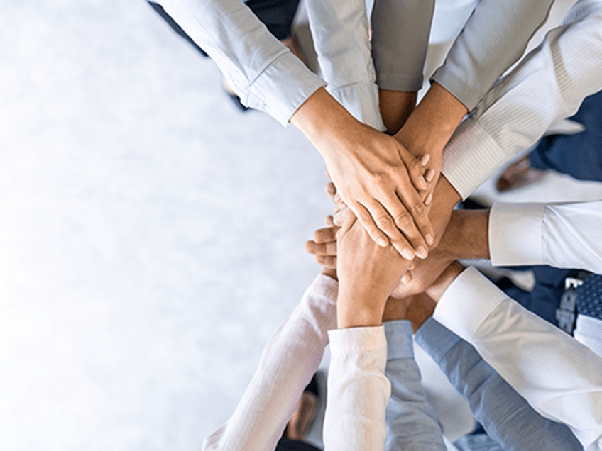 an image of a team putting their hands together